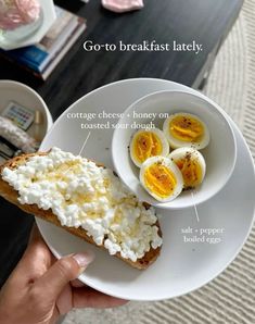 a person holding a plate with eggs and bread on it