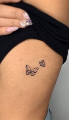 a woman's stomach with two butterflies tattoo on the side of her thigh,