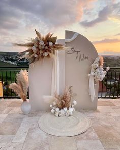 an outdoor ceremony setup with flowers and feathers on the ground in front of a sunset sky