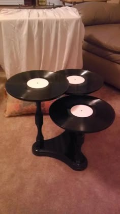 three black vinyl record tables sitting on the floor in front of a couch and coffee table