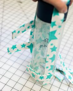 someone is holding a roll of tape and wrapping it around a tube with stars on it