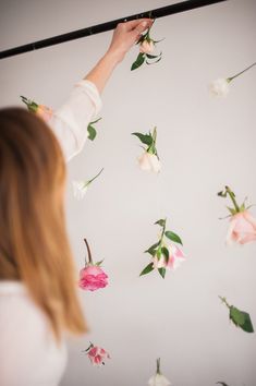 a woman standing in front of a wall with flowers on it