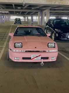 two pink cars parked in a parking garage