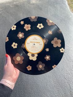 a woman's hand holding up a record with flowers on it