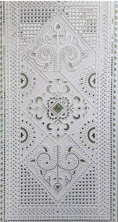 an intricately designed wall hanging in white with green accents and designs on the side