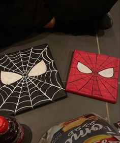 two spider - man coasters are sitting on the floor next to soda cans and candy