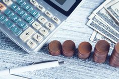 a calculator sitting on top of a wooden table next to stacks of money