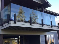 a balcony with glass railings on the top and side of a house in the background