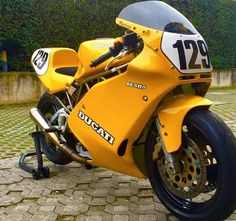 a yellow motorcycle parked on top of a cobblestone road