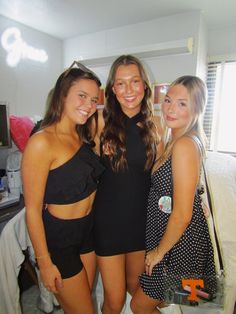 three young women standing next to each other in front of a bed with white sheets