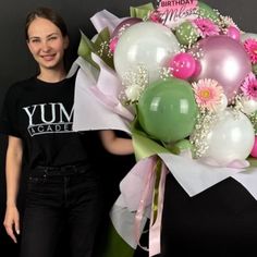 a woman holding a bouquet of balloons and flowers