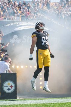 a football player jumping up into the air with his arms in the air and people watching