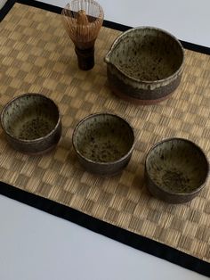 four bowls and a whisk sitting on top of a mat