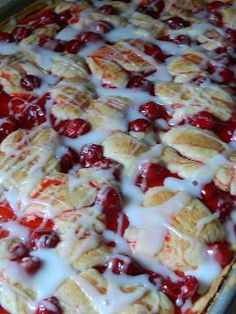 a close up of a pie with cherries on it and white sauce drizzled over the top