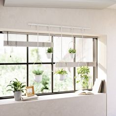 a window sill filled with potted plants next to a book and framed photograph