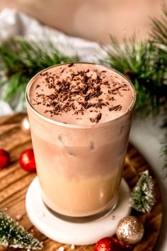 a drink is sitting on a wooden board with christmas decorations and greenery around it