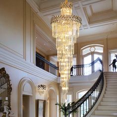 a chandelier hanging from the ceiling in a large room with two staircases