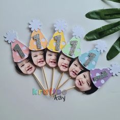 a group of children's birthday hats with the number one on them and flowers