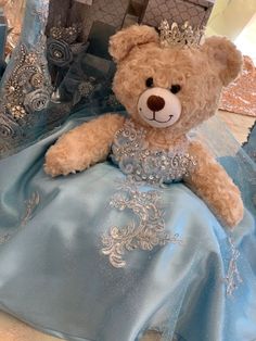 a brown teddy bear wearing a blue dress with a tiara on it's head