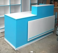 a blue and white reception desk in a room with shelves on the wall behind it