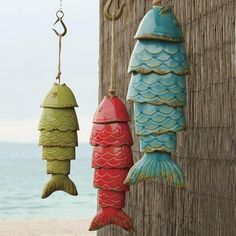 two colorful fish hanging from hooks next to the ocean