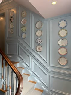 plates are arranged on the wall next to the stair case in this elegant entryway