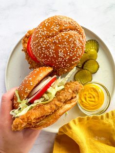 a chicken sandwich and pickles on a plate