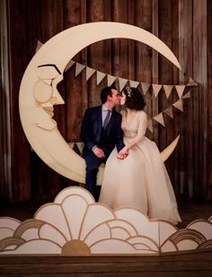 a man and woman are kissing in front of a photo booth with the moon on it