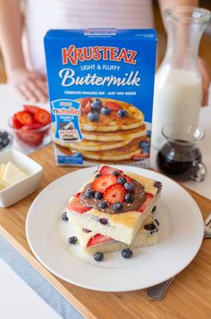 a white plate topped with cake next to a box of blueberries and strawberries