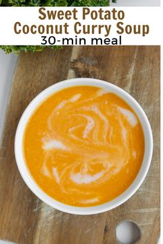 sweet potato coconut curry soup in a white bowl on a wooden cutting board with spoon