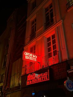 a red neon sign is lit up on the side of a building in paris, france