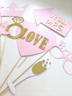 pink and gold photo booth props for a bachelor's day party on a white table