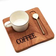 a coffee cup and spoon on a wooden coaster with the word coffee printed on it