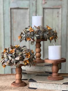 two wooden candlesticks with flowers and leaves in them on top of an old book