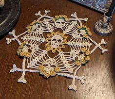 a crocheted doily sits on a table next to a pen and ink pot