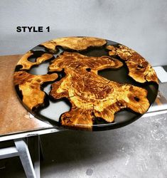 a wooden table with black and brown designs on it's surface, sitting on a metal stand