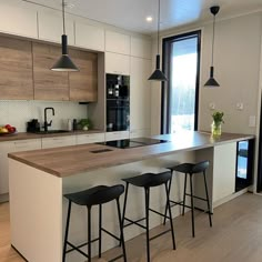 a kitchen with an island and three stools in front of the counter top that is made out of wood