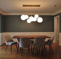 a dining room table with four chairs and a light fixture hanging from it's ceiling