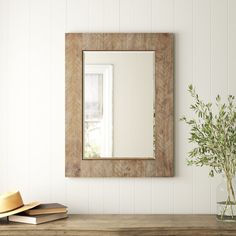 a mirror sitting on top of a wooden table next to a vase filled with flowers