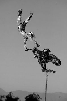 a person on a dirt bike does a trick in the air over a street light