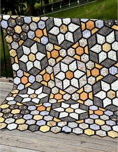 a quilt that is sitting on top of a wooden table in front of some grass