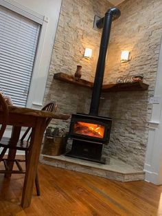 a wood burning stove sitting inside of a living room next to a table and chairs