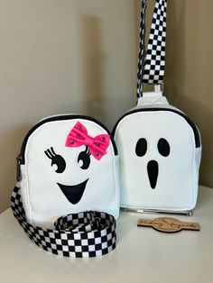 It's always spooky season with this adorable Ghost Sling! This cute little sling is the perfect grab n' go size.  Carry all of the essentials within easy reach; this sling just right for a phone, wallet, keys, sunglasses and maybe a snack or two :) A white faux leather body looks great with the hand appliquéd ghost details. The adjustable black and white checkered strap can be clipped on either side of the bag for either right or left handed wear.  A waterproof interior and a small interior zipp Cute Bags For Everyday Use And Halloween, Halloween White Backpack, White Backpack For Halloween, White Halloween Backpack, Boo Boo Bags, Small Sling Bag, Coin Purse Wallet, Work Ideas, Coin Purses