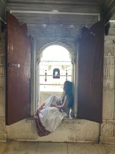 a woman sitting on the ledge of a building