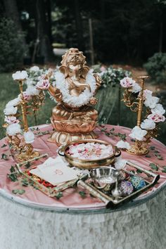 a small statue sitting on top of a table covered in pink and white cloths