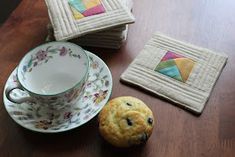 there is a cup, saucer and cookie on the table next to each other