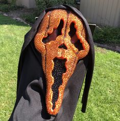 an orange and black mask sitting on the back of a person's pants in front of a house