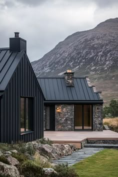 a black house with mountains in the background