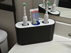 there are four toothbrushes in the holder on the bathroom sink counter next to the mirror