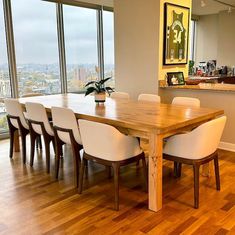 a dining room table with white chairs in front of large window overlooking cityscape